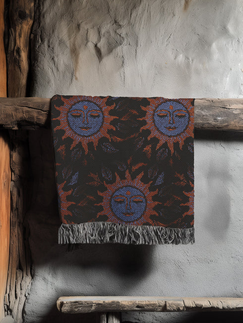 Luxurious woven cotton throw blanket featuring mystical blue sun faces with copper rays on black background, bordered by elegant fringe. Perfect celestial wall hanging, witchy bedroom decor, or dark academia throw for couch or bed.